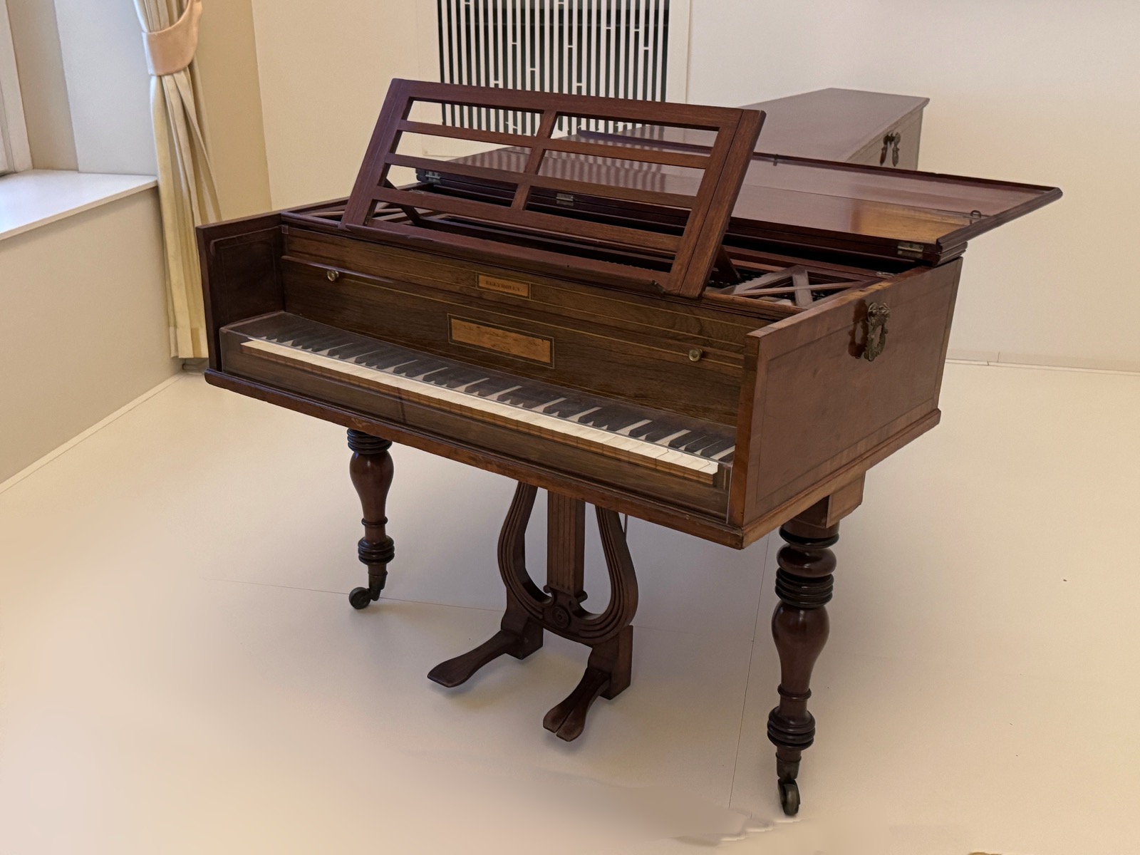 An early nineteenth-century Broadwood grand fortepiano displayed in a museum, with a wooden case and music stand