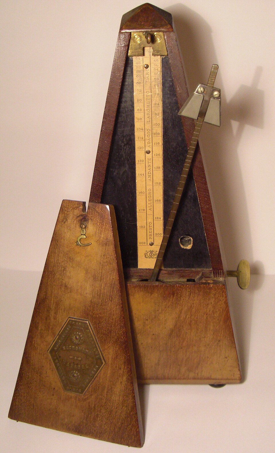 Wooden pyramid-shaped mechanical metronome of the Maelzel type with exposed pendulum and tempo scale