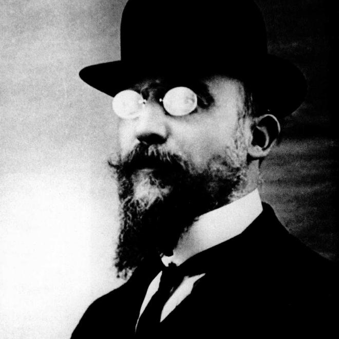 Black and white photographic portrait of composer Erik Satie wearing a bowler hat, pince-nez glasses and a beard, around 1909