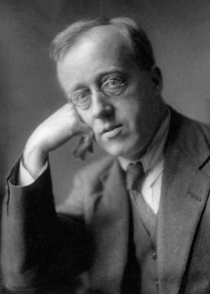 Portrait photograph of English composer Gustav Holst wearing round glasses