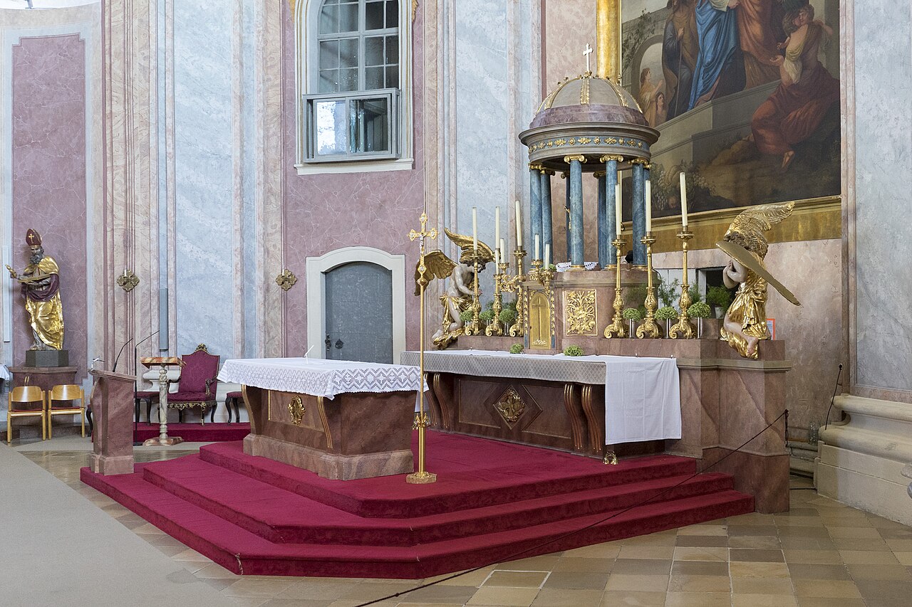 Baroque interior of the Bergkirche in Eisenstadt, Austria, showing the gilded high altar and red-carpeted steps