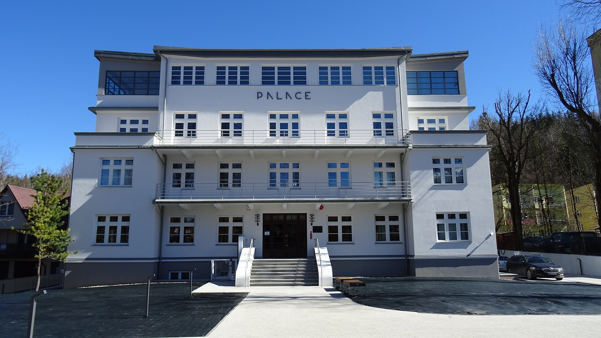 The white facade of the Palace building in Zakopane, Poland, a former Gestapo headquarters now a museum, with mountains behind it