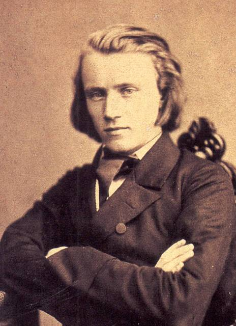 Sepia photographic portrait of the young Johannes Brahms with folded arms, 1853