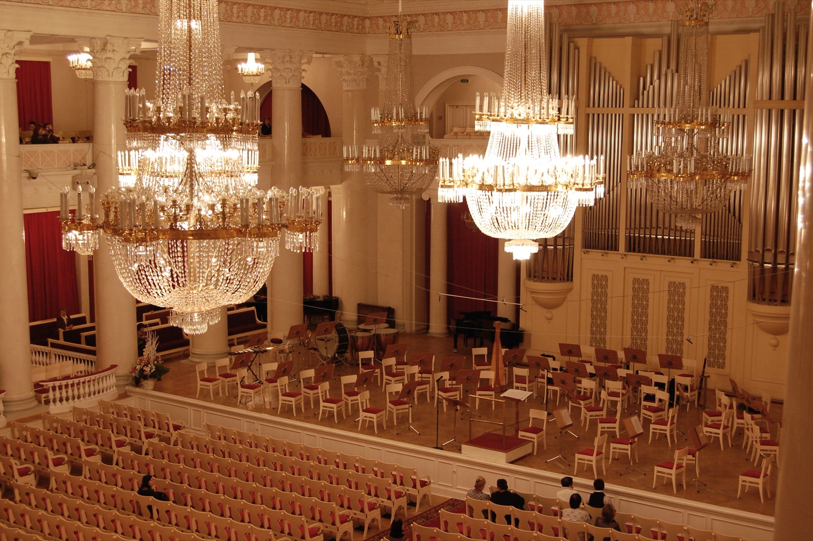 Interior of the Grand Hall of the Saint Petersburg Philharmonia, with chandeliers, white columns and the organ facade behind the stage