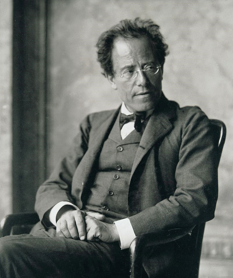 Black and white portrait photograph of the composer Gustav Mahler seated, wearing round spectacles and a dark suit