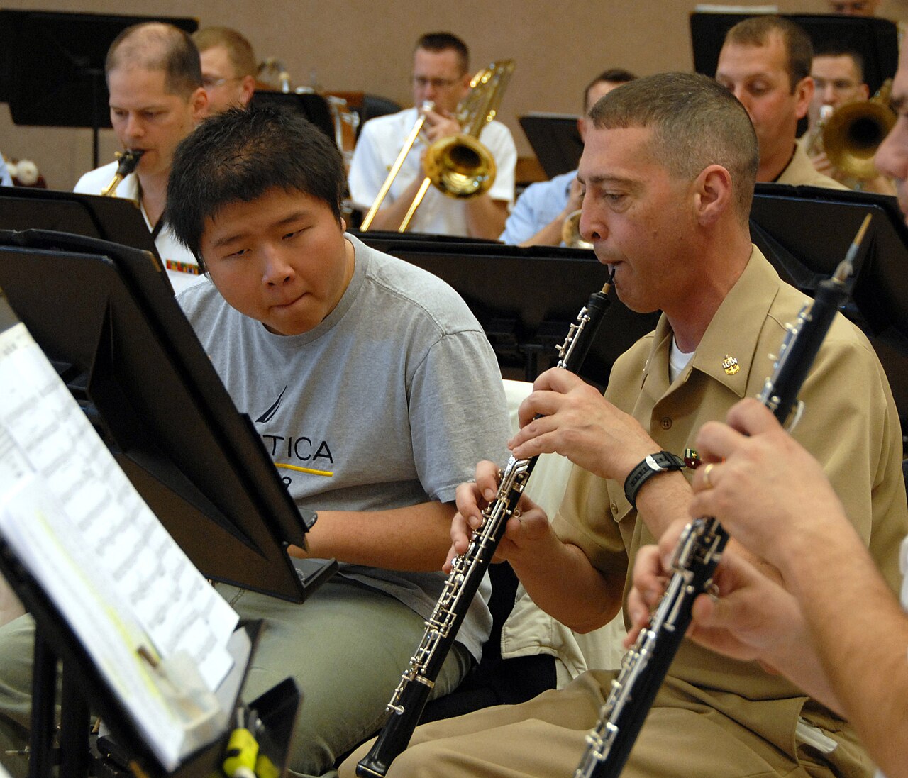 Two oboists playing, with the double reed held between the lips and the fingers on the keys