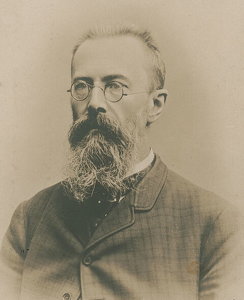 Sepia photograph of the bearded composer Nikolai Rimsky-Korsakov wearing round spectacles and a dark suit