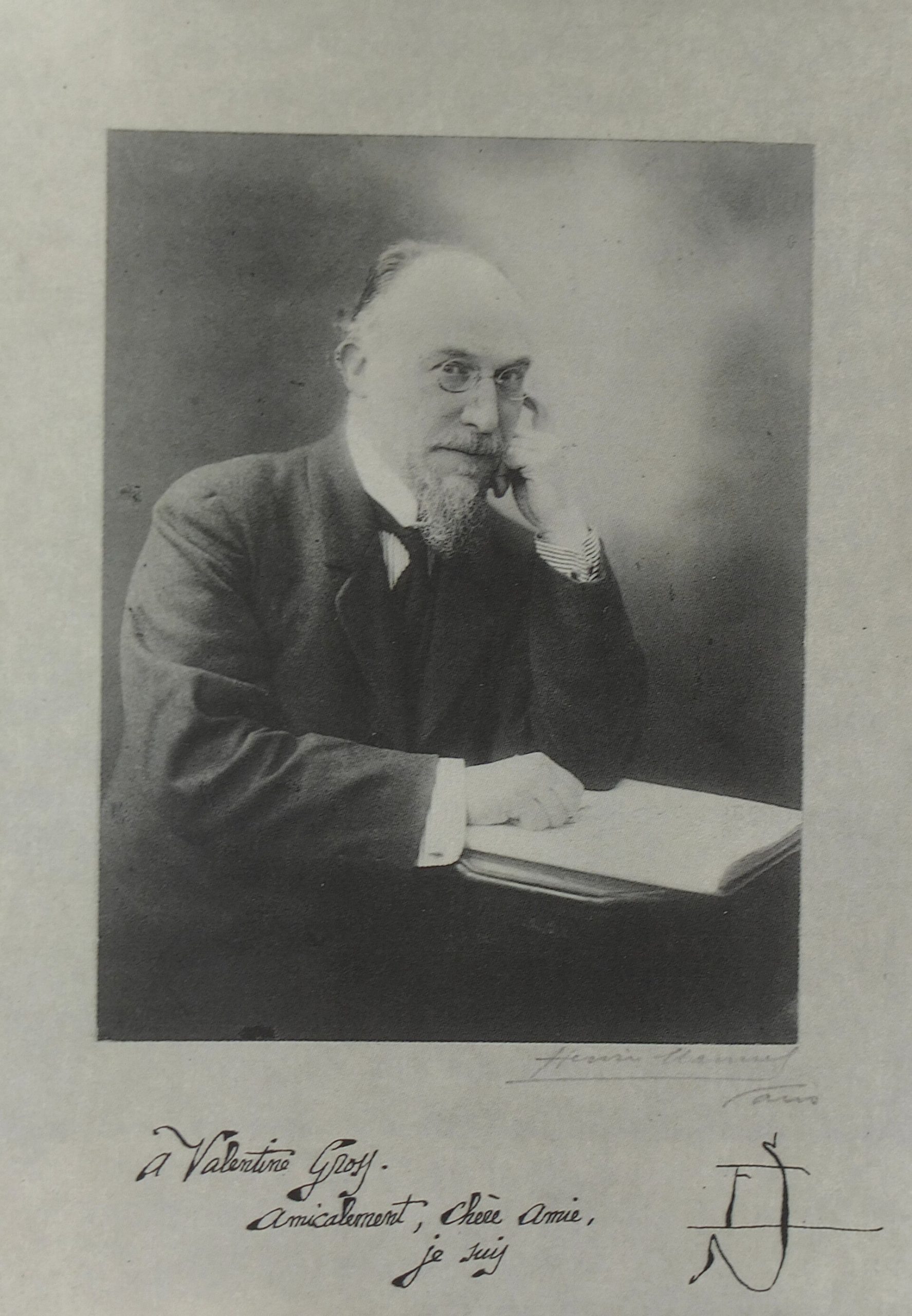 Photographic portrait of the French composer Erik Satie by Henri Manuel, seated at a desk