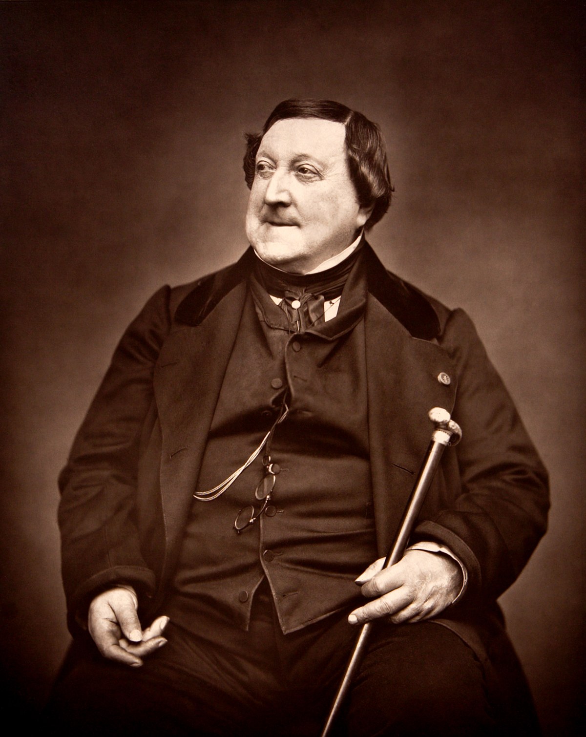 Sepia photographic portrait of the composer Gioachino Rossini seated with a cane, taken by Etienne Carjat in 1865