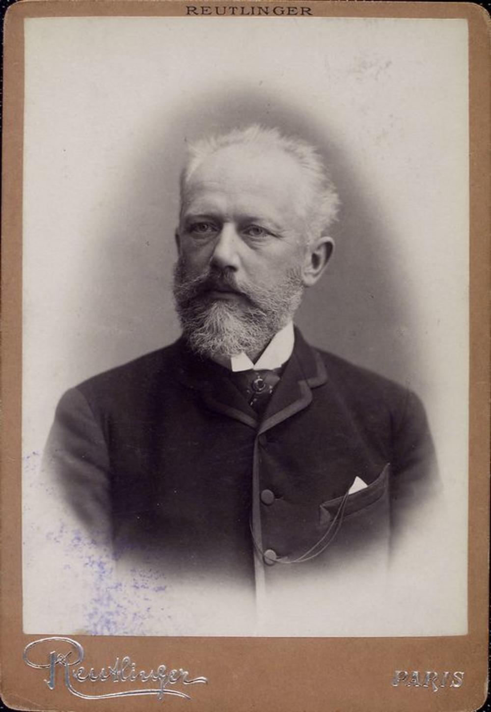 Studio photographic portrait of composer Pyotr Ilyich Tchaikovsky with white hair and beard, wearing a formal jacket