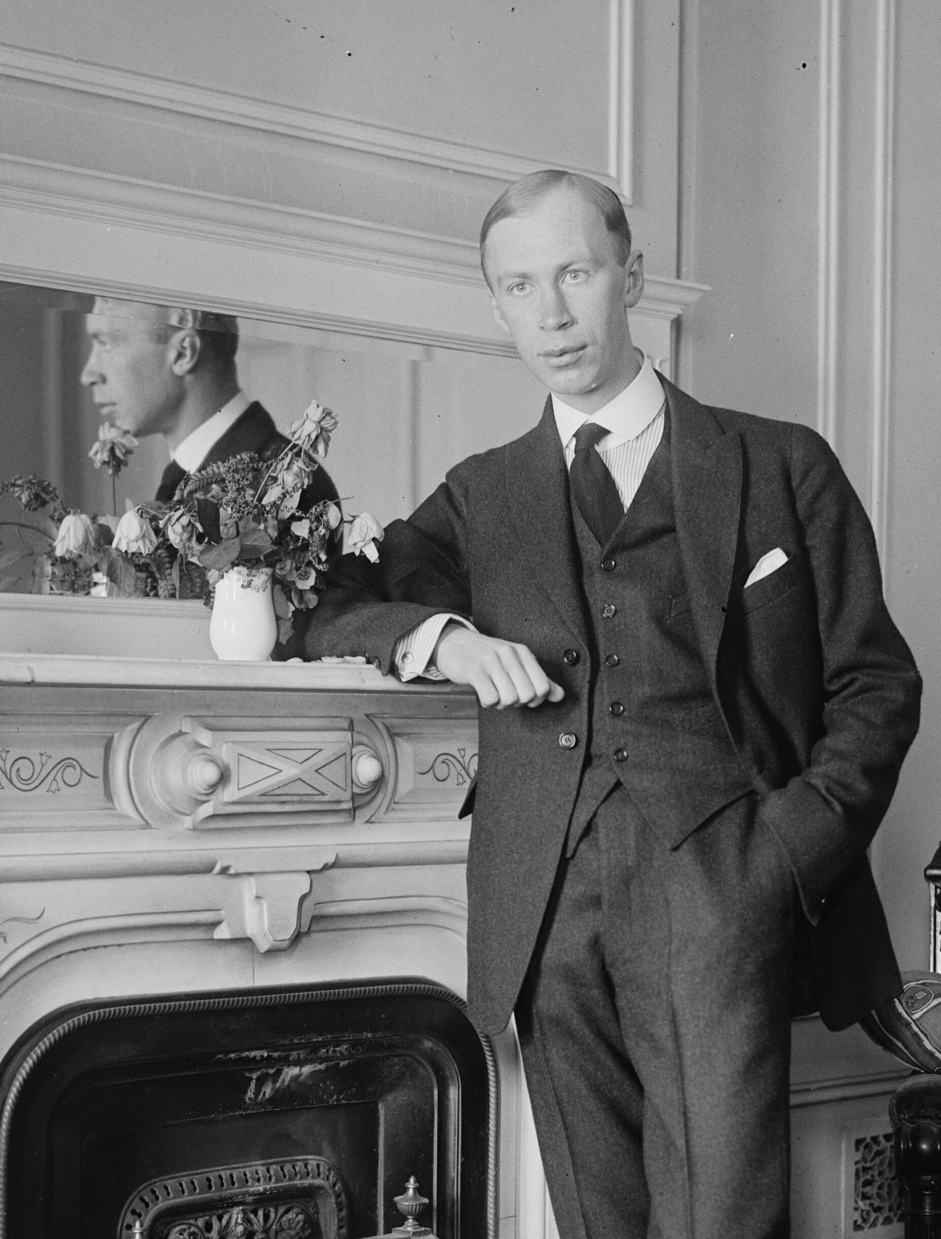 Black and white photograph of the young composer Sergei Prokofiev leaning against a fireplace