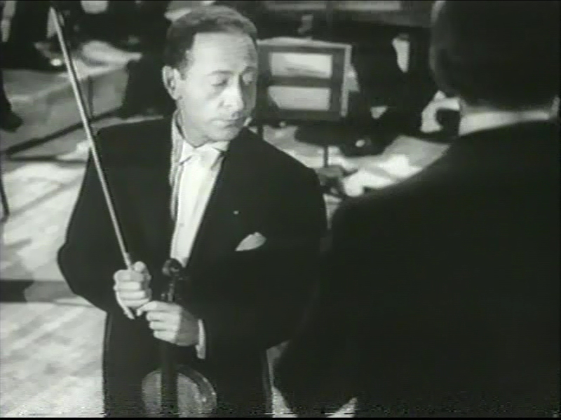 Black and white photograph of violinist Jascha Heifetz standing with violin and bow at Carnegie Hall